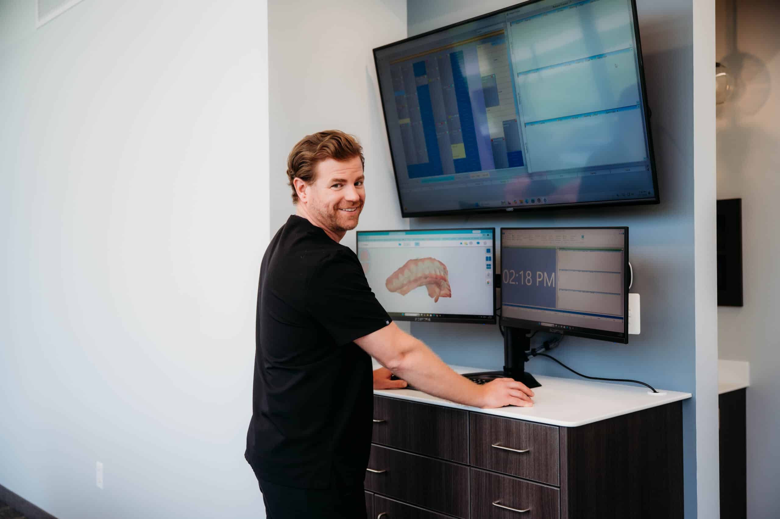 Dr. Andrew DeHaan reviewing a 3D dental scan on multiple screens at a digital workstation at DeHaan Orthodontics in Lake Orion, MI
