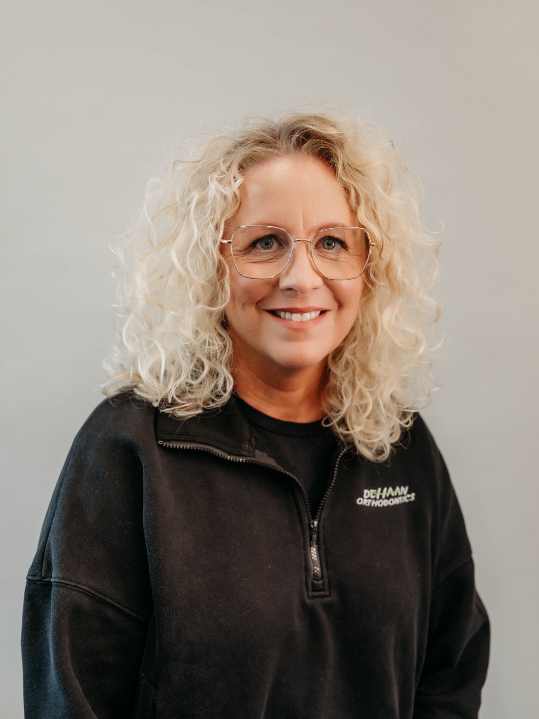 Julie, Treatment Coordinator at DeHaan Orthodontics, smiling in a branded team jacket at DeHaan Orthodontics in Lake Orion, MI