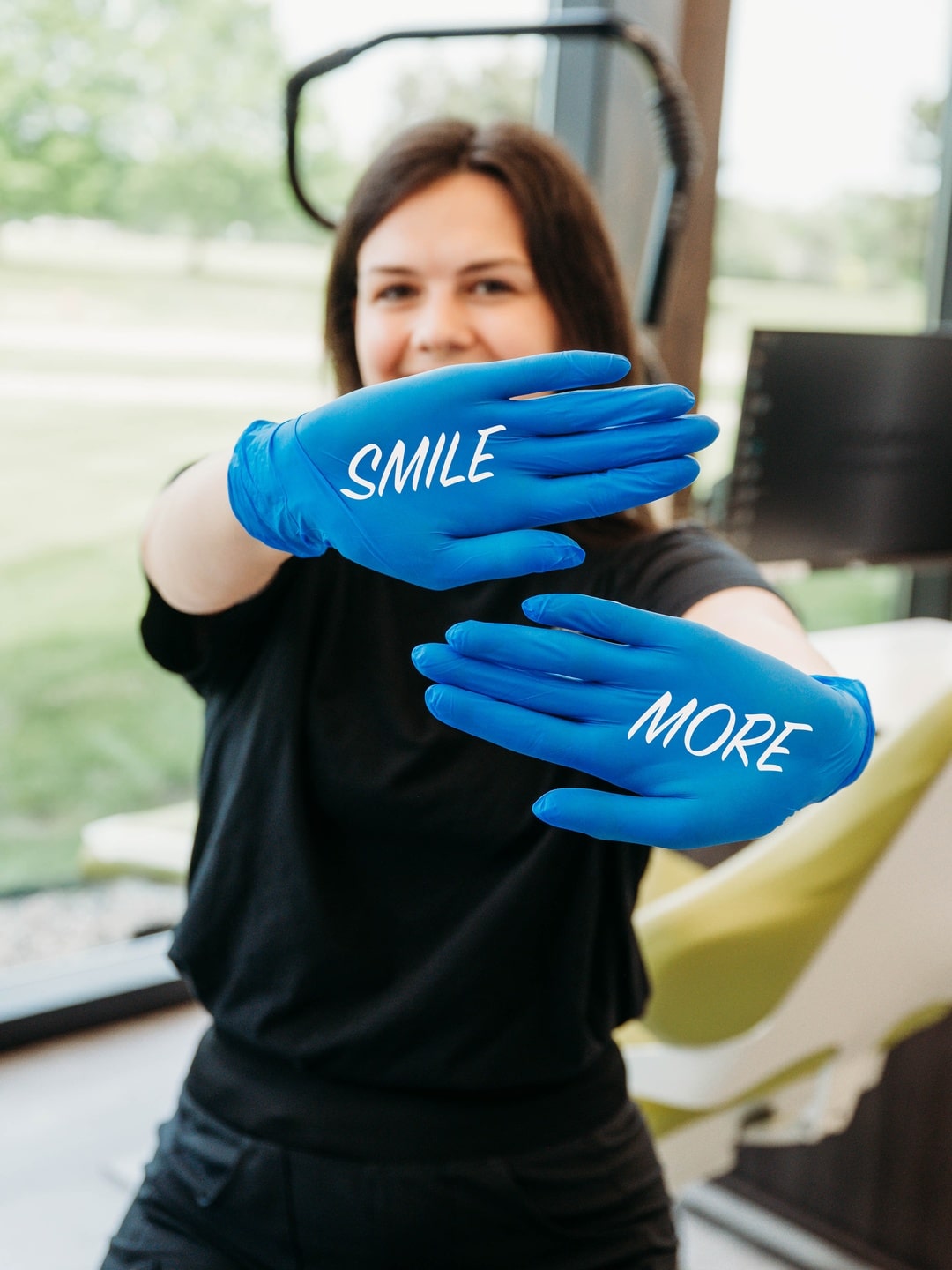 Team member holding up blue gloves that read Smile More in the treatment area at DeHaan Orthodontics in Lake Orion, MI