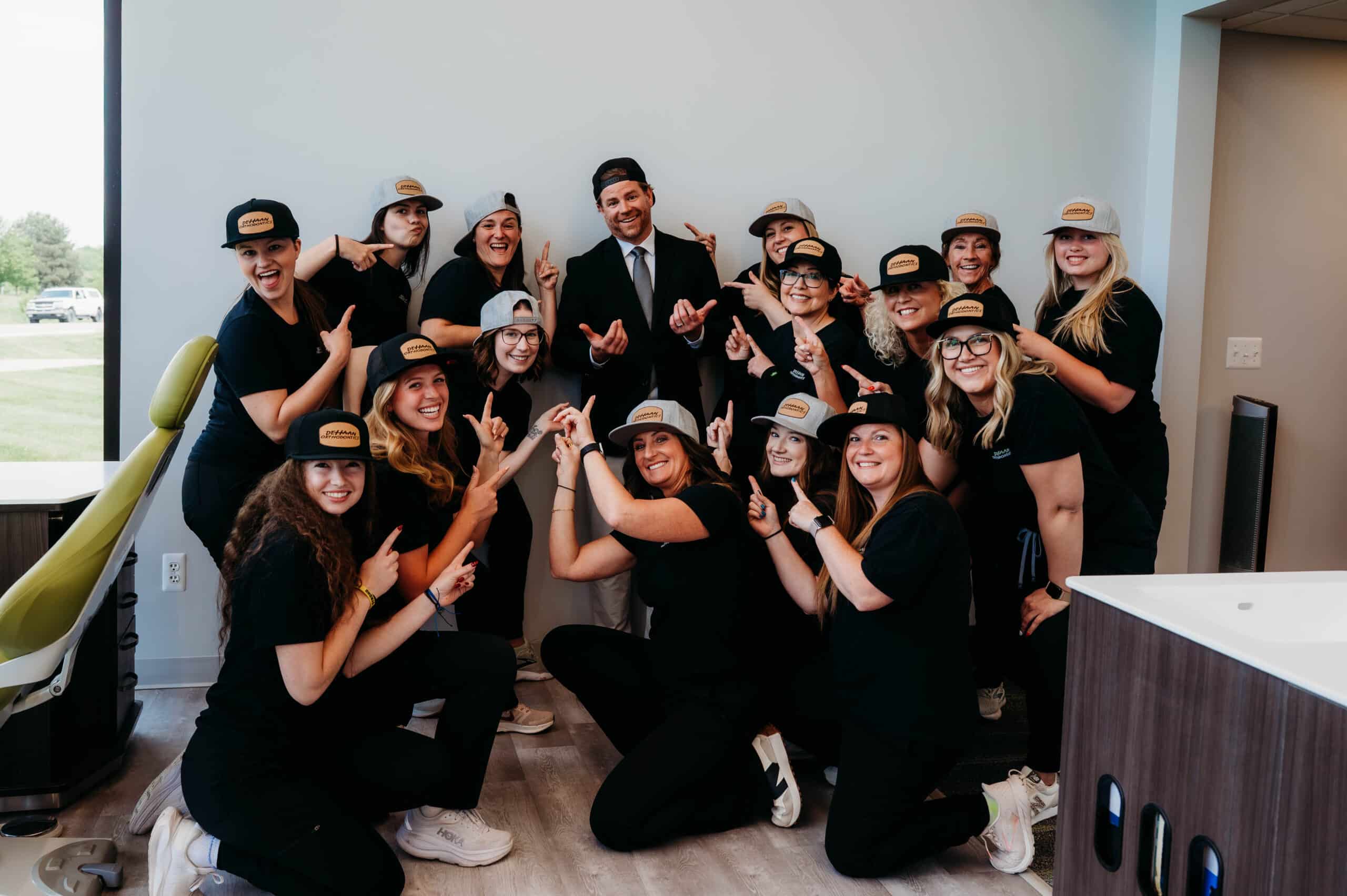 Dr. DeHaan and the team posing playfully together in matching hats inside the office at DeHaan Orthodontics in Lake Orion, MI